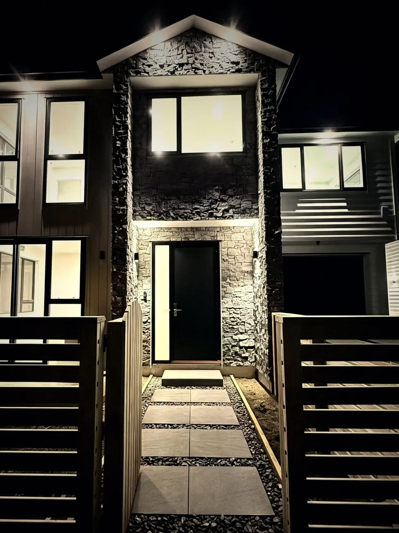 Stone-clad entrance with lit pathway at night
