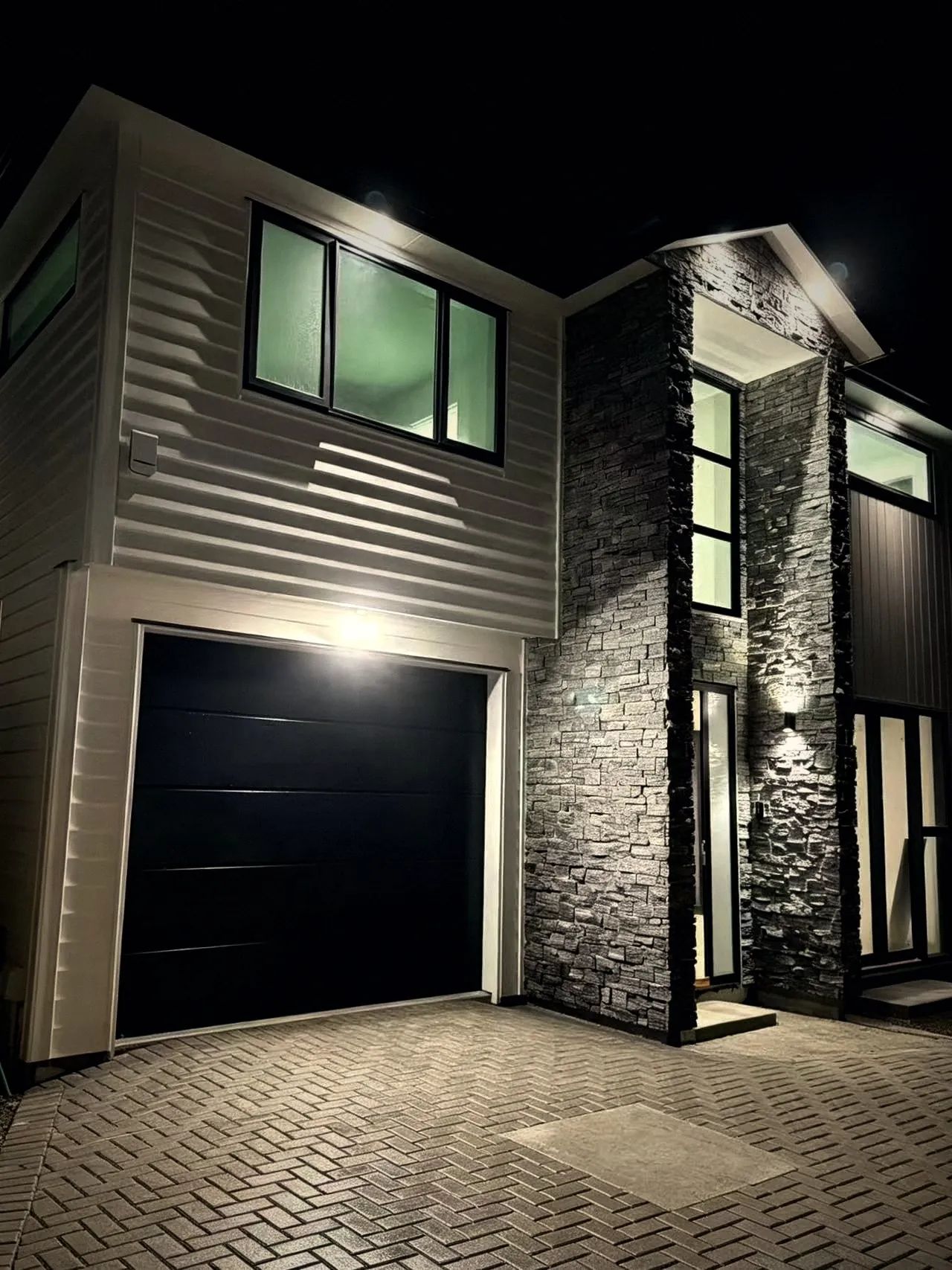 Stacked stone feature wall and garage at night